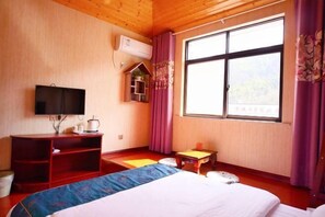 Une chambre d’hôtel avec un lit, une télévision, une petite table, une fenêtre et un plafond en bois.