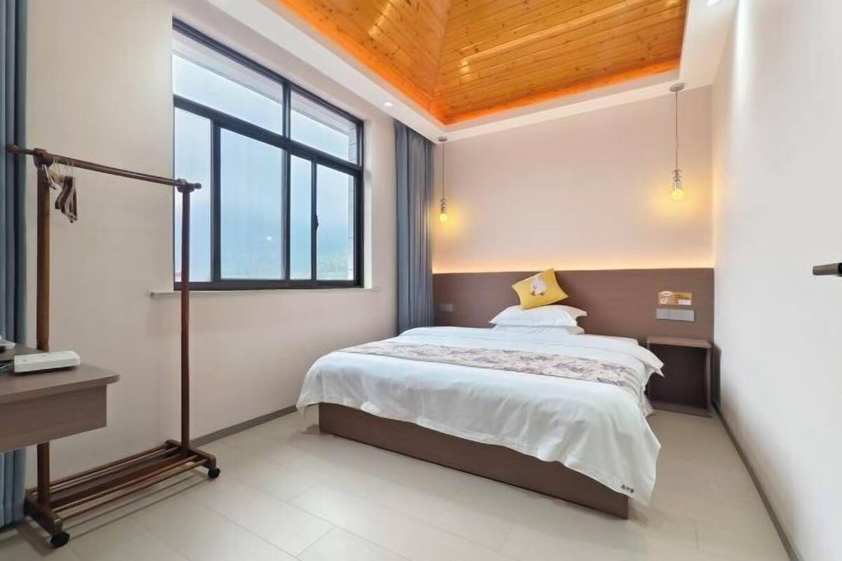 Une chambre à coucher avec un lit, une table de chevet, une fenêtre et un plafond en bois.