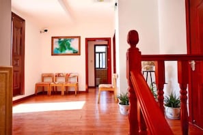 A hallway with wooden flooring, a red staircase, and a seating area with chairs. - Ningguo Travellers Homestay (Ningguo)
