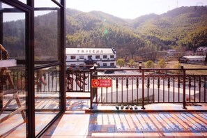 Une chambre d’hôtel avec vue sur un paysage montagneux, un balcon doté d’une rambarde en métal et un panneau indiquant un espace réservé aux fumeurs.