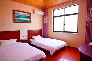 Une chambre d’hôtel avec deux lits, une grande fenêtre, un tableau au mur et un appareil de climatisation.