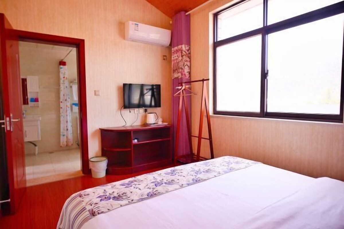 Une chambre d’hôtel avec un lit, une télévision, un petit bureau et une fenêtre avec des rideaux.
