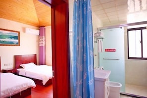 Une chambre d’hôtel avec deux lits, une salle de bain avec un lavabo et des toilettes, et une porte sur laquelle est apposé un panneau d’avertissement.