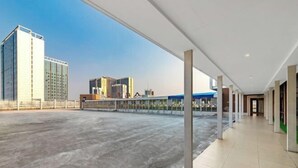 A spacious indoor area with a concrete floor and a corridor with columns. - Venus International Hotel (Foshan)