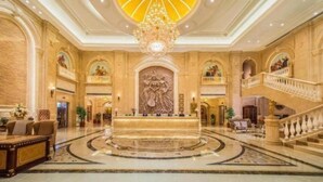A grand lobby with a central reception desk, a large chandelier, and a grand staircase. - Venus International Hotel (Foshan)