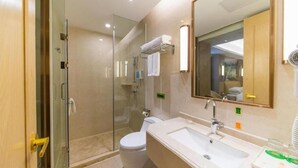 A modern bathroom with a glass-enclosed shower, a white toilet, a sink with a mirror, and a towel rack. - Venus International Hotel (Foshan)