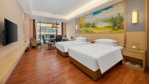 A hotel room with two beds, a desk, chairs, a TV, and a painting on the wall. - Venus International Hotel (Foshan)