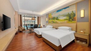 A hotel room with two beds, a desk, a chair, a TV, and a painting on the wall. - Venus International Hotel (Foshan)