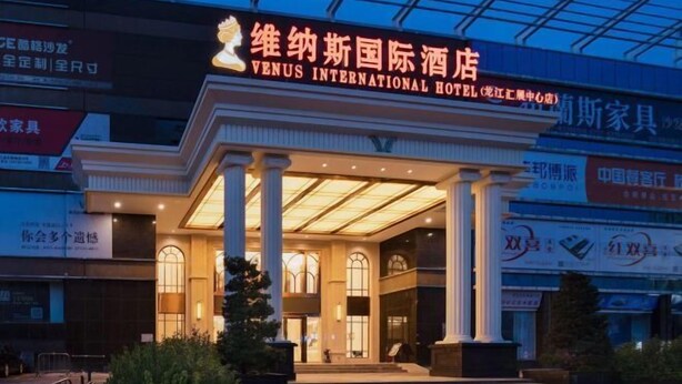 The exterior of the Venus International Hotel with a prominent entrance, large columns, and illuminated signage. - Venus International Hotel (Foshan)
