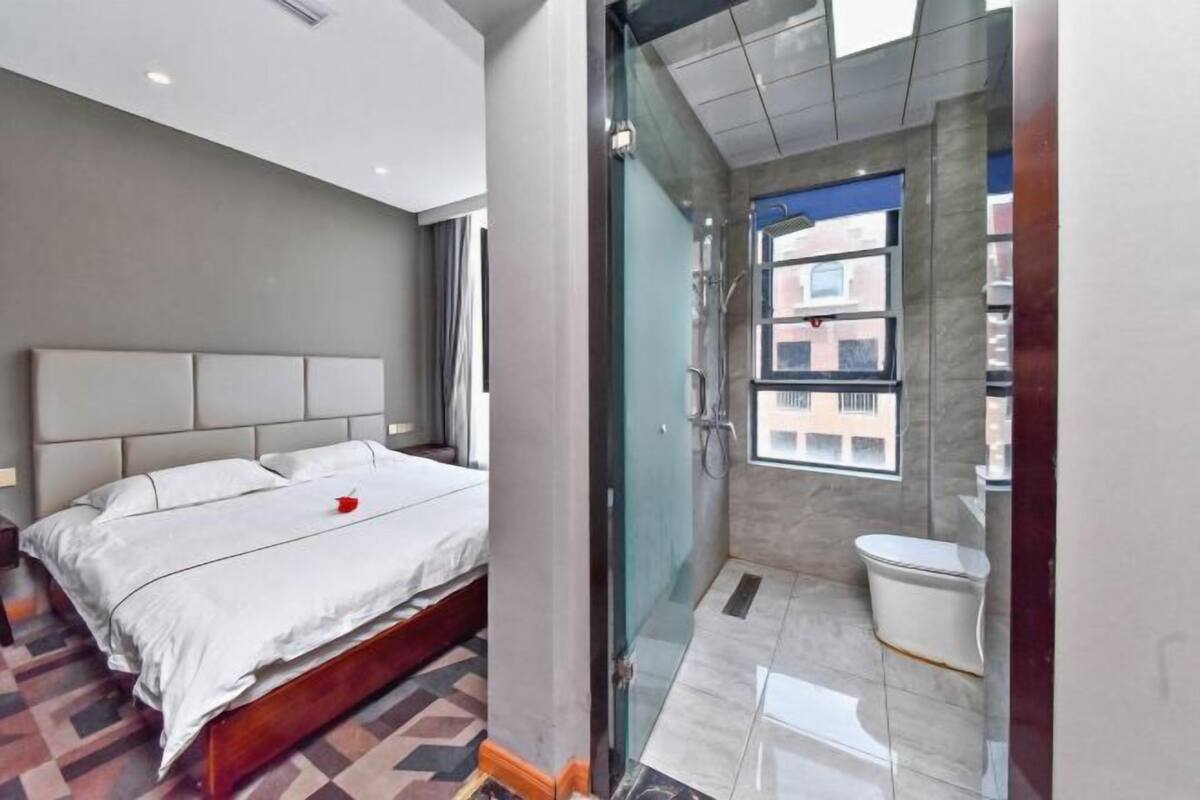 Une chambre d’hôtel moderne dotée d’un grand lit, d’une douche en verre et offrant une vue sur la ville.