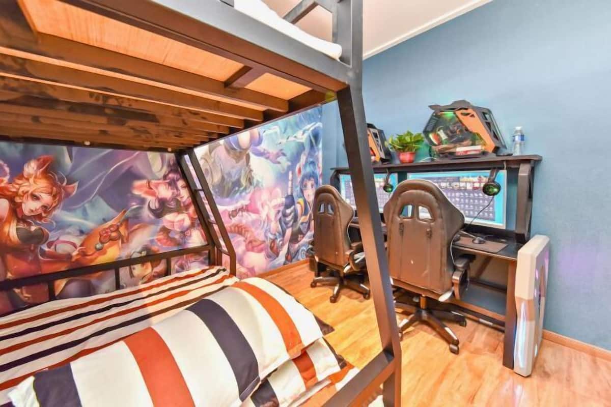 Un lit superposé orné d’une fresque colorée, un bureau avec un ordinateur et une chaise.