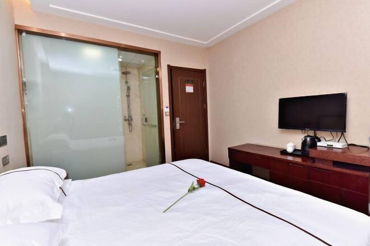 Une chambre d’hôtel équipée d’un lit, d’une télévision, d’un bureau et d’une porte coulissante donnant accès  à une zone douche.