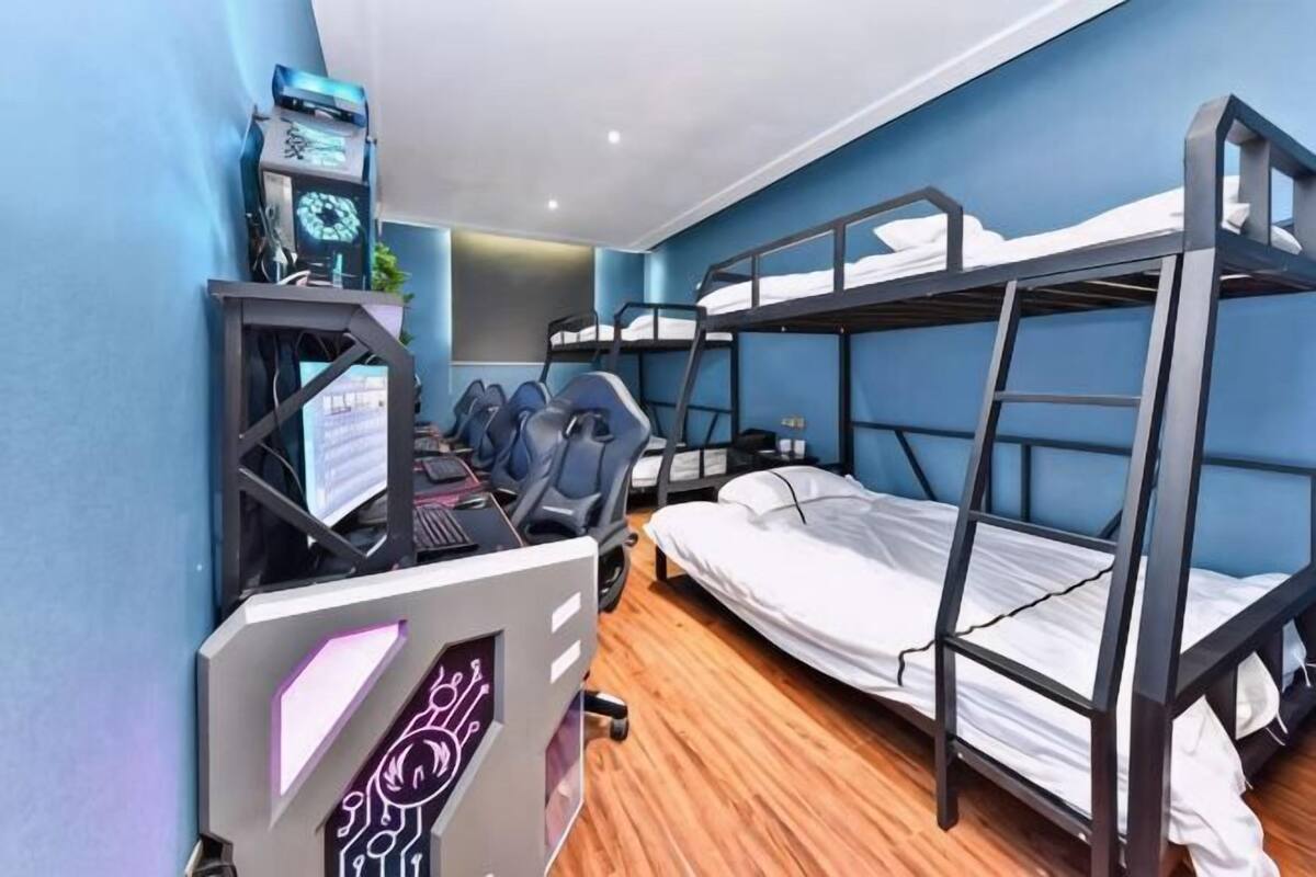 Une chambre avec un lit superposé, un bureau, une chaise et un ordinateur.