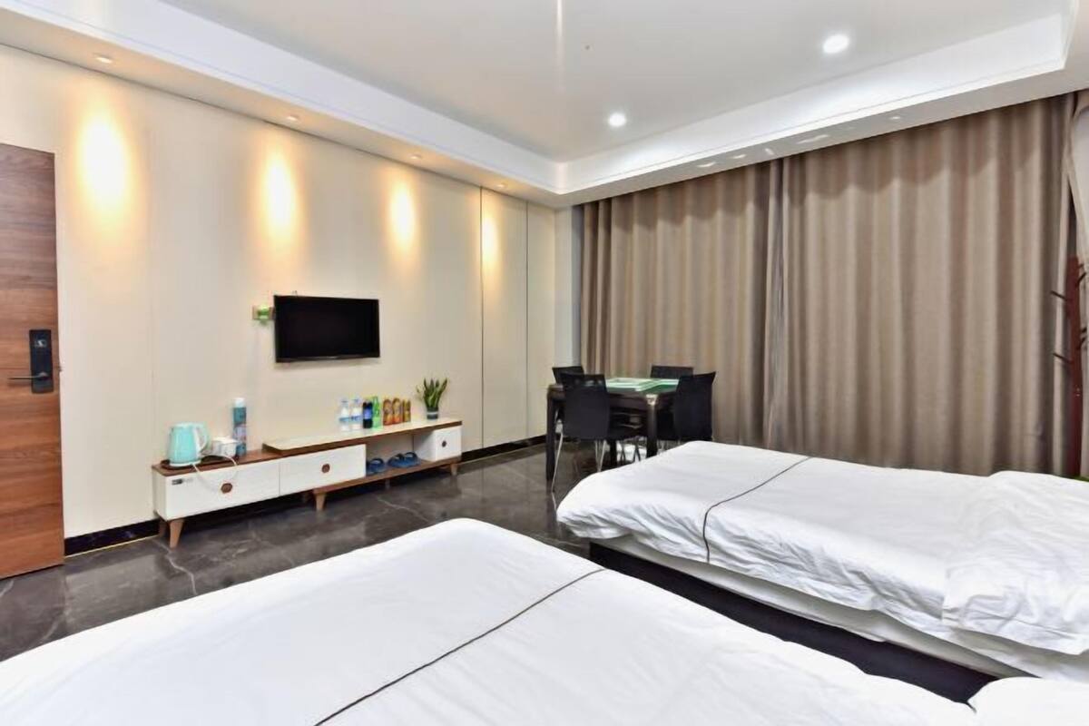 Une chambre d’hôtel avec deux lits, un bureau, une chaise, une télévision et un mini-bar.