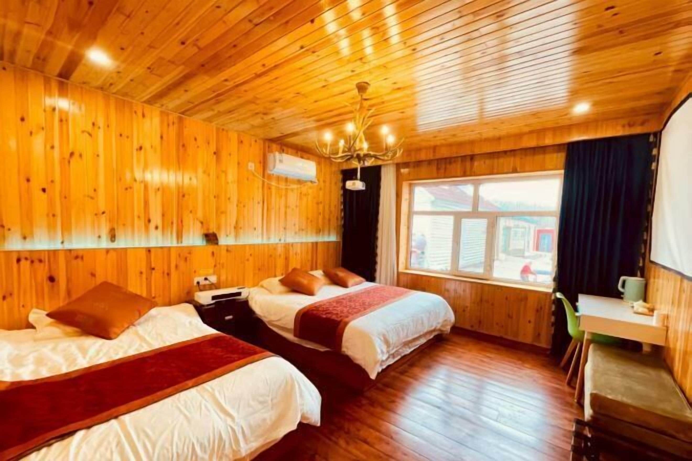 Una habitación con paneles de madera, dos camas, un escritorio y una ventana.