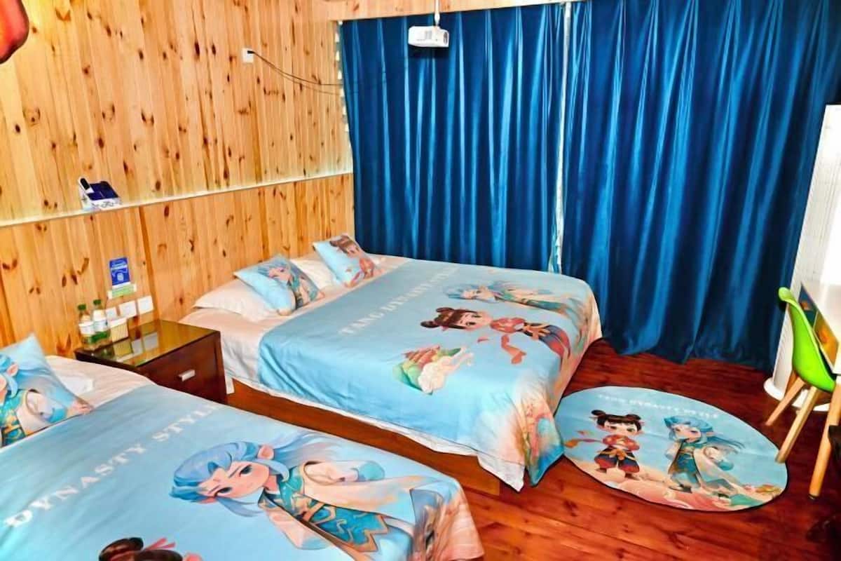 A room with two beds, wooden walls, a blue curtain, and a green chair.