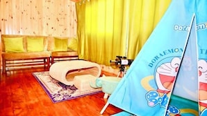 A wooden room with a sofa, curtains, a camera on a tripod, and a tent with a Doraemon design. - Time Inn (Linjiang Branch, Shiwei Town, Erguna) (Ergun)