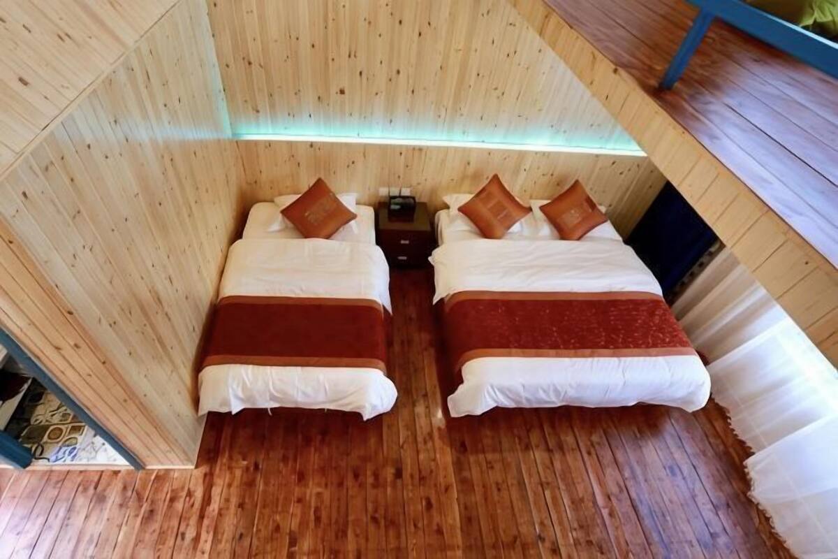 A room with two beds, wooden walls, and a wooden floor.
