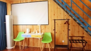 A room with a wooden interior, a desk with a chair, a projector screen, and a staircase. - Time Inn (Linjiang Branch, Shiwei Town, Erguna) (Ergun)