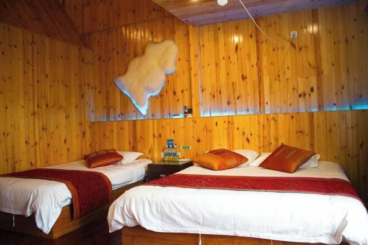 A room with two beds, wooden walls, a wooden ceiling, and a mounted television.