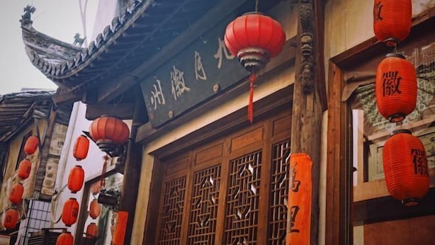 A traditional building with ornate wooden doors and red lanterns. - September Huizhou Inn (She County)