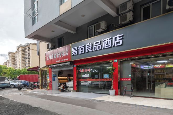 A building with a storefront that has a sign indicating it is a liquor store. There are parked cars and a motorcycle outside.