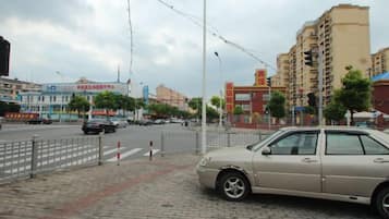 A street view with a parked car, buildings, and a pedestrian crossing.