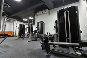 Een fitnessruimte met diverse trainingsapparaten, waaronder krachtapparaten en losse gewichten.