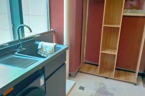 A kitchen with a sink, a window, and a wooden shelving unit. - Meike City Hotel (Ningbo)