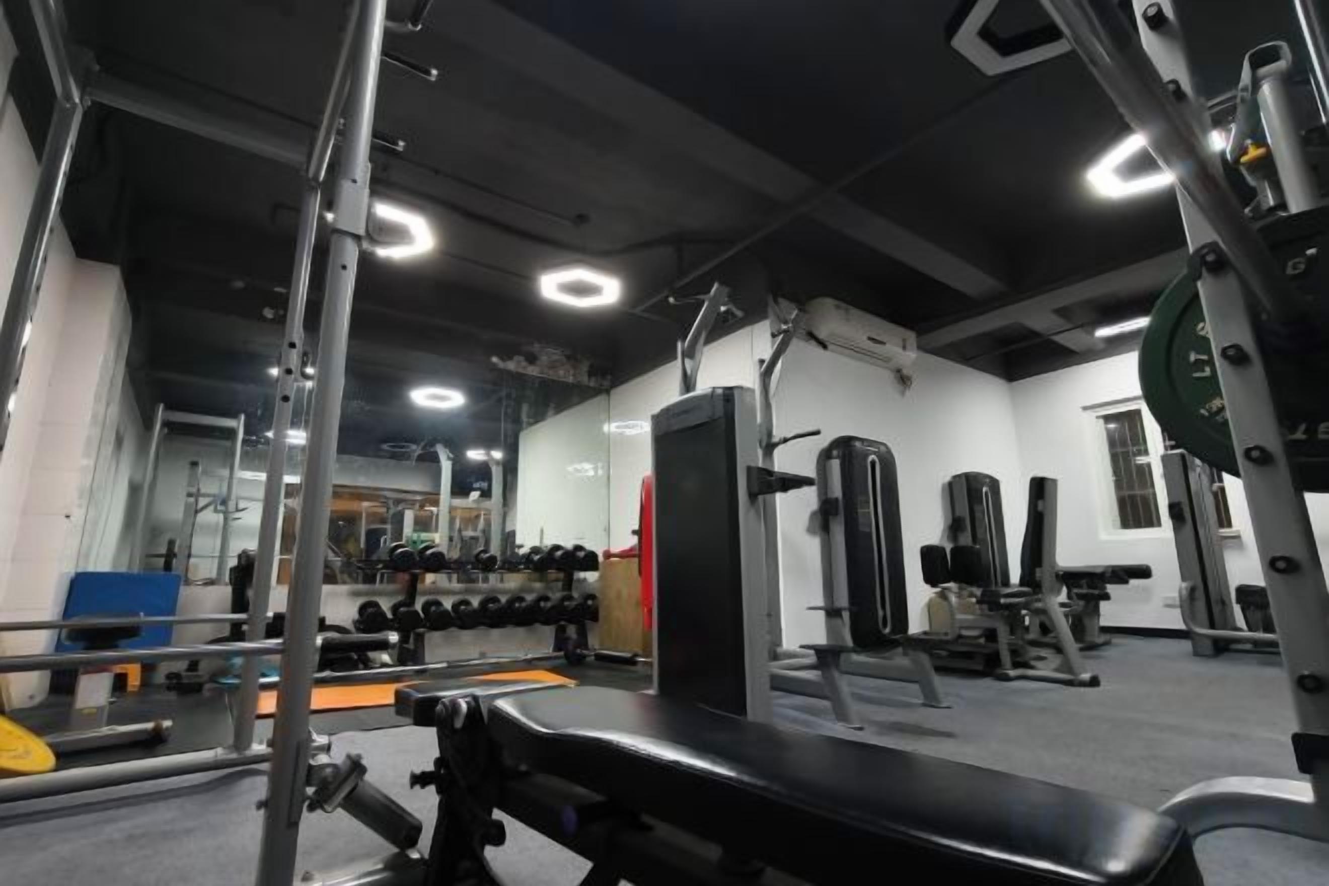 A gym with weightlifting equipment, benches, and mirrors.