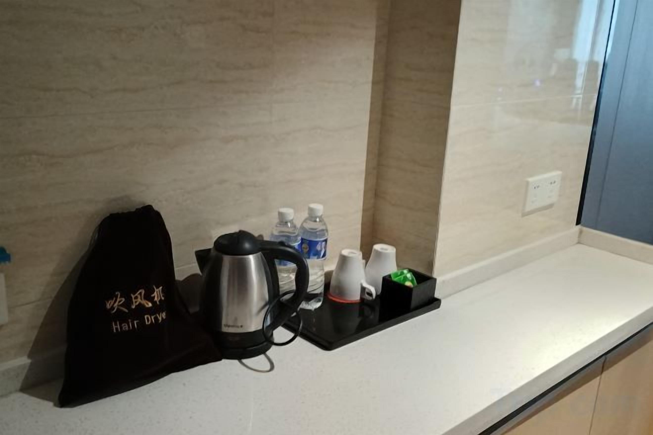 Ein Hotelzimmerzähler mit Wasserkocher, Wasserflaschen, einer Tasse und einem Haartrockner.