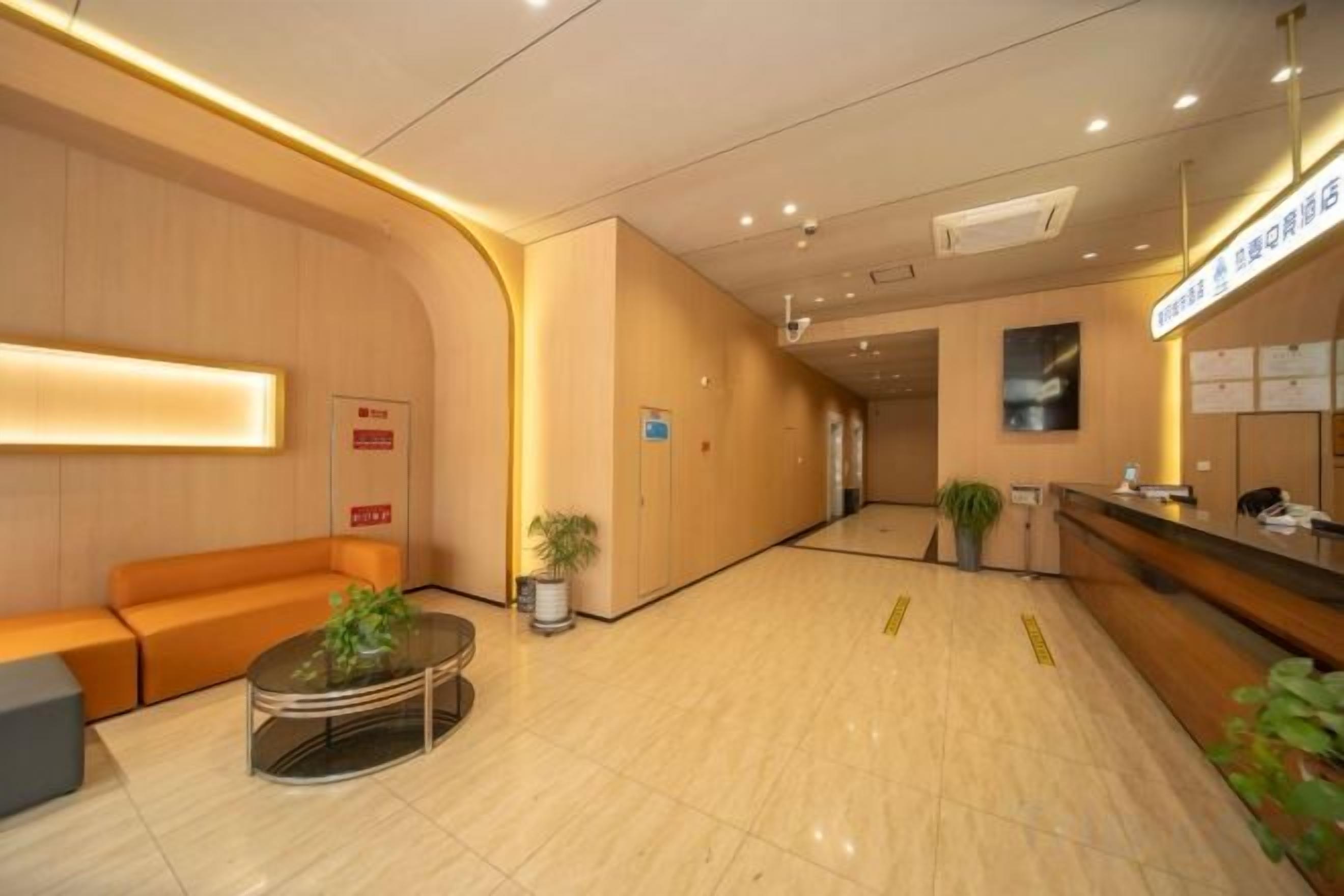A hotel lobby with a reception desk, seating area, and a plant.