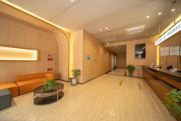 Vestíbulo de hotel con mostrador de recepción, zona de estar y una planta.