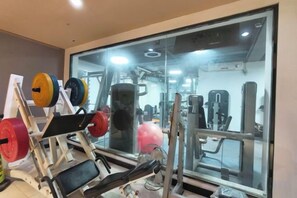 Un gimnasio con equipo de levantamiento de pesas, un espejo y máquinas de ejercicio.