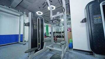 A gym with exercise equipment, a mirror, and a weight rack.