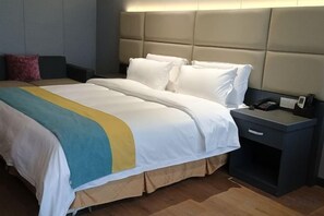Una habitación de hotel con una cama grande, una mesita de noche con teléfono y un cabecero.