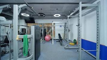 A gym with various exercise equipment, including weight machines and a ball.