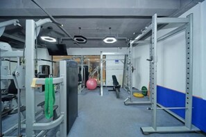 A gym with various exercise equipment, including weight machines and a ball. - Meike City Hotel (Ningbo)