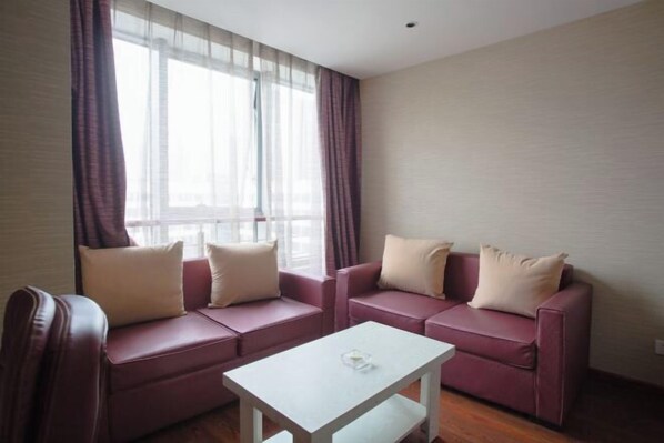 A room with two sofas, a small white table, and a window with sheer curtains.