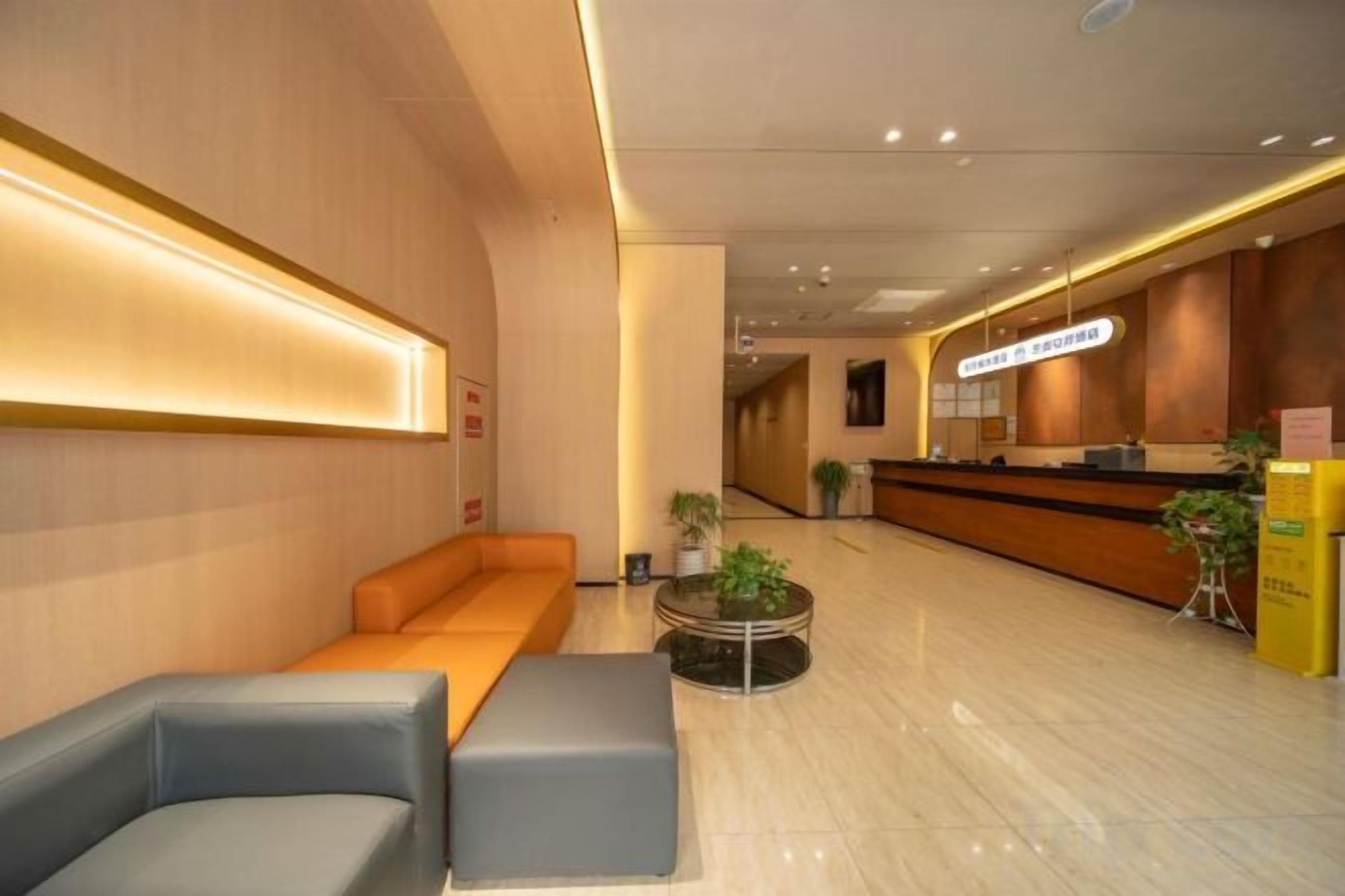 Um saguão de hotel com balcão de recepção, área de estar e uma planta.