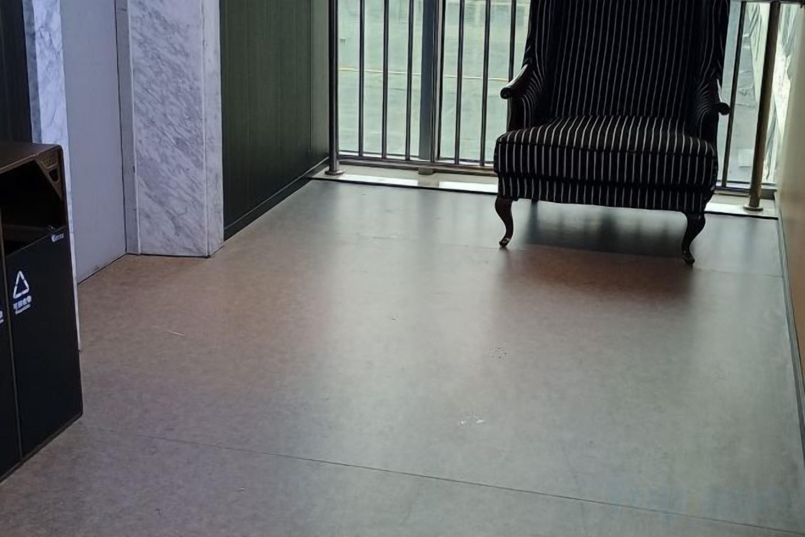 A room with a tiled floor, a trash bin, a chair, and a glass door leading to an outdoor area.