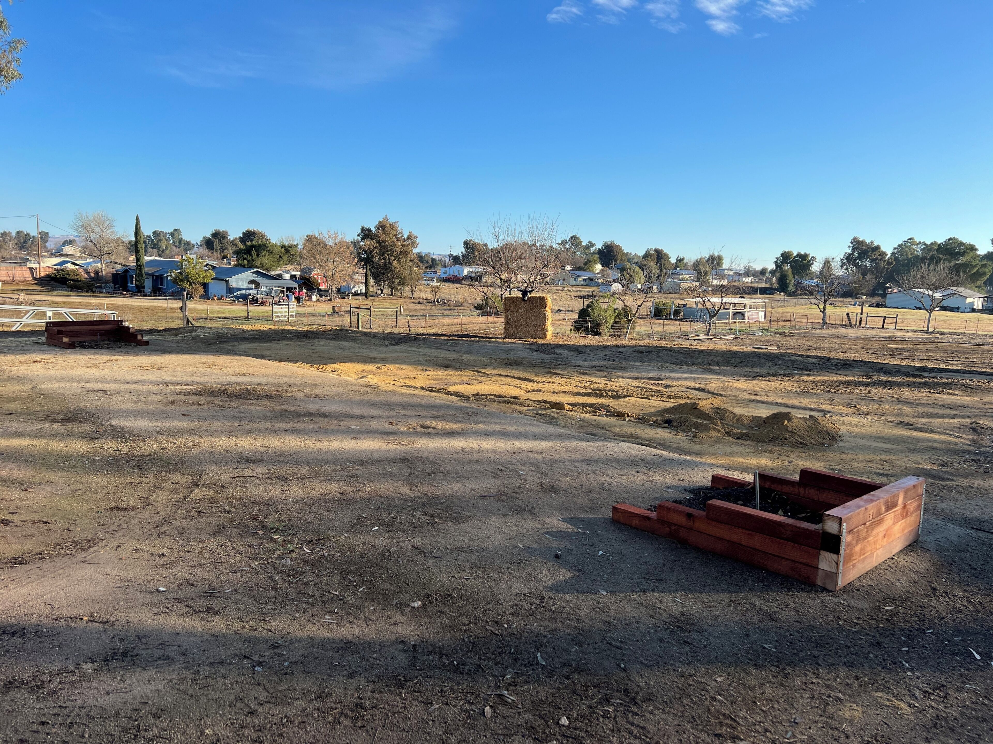 Un paisaje rural con campos abiertos, fardos de heno y construcciones de madera.