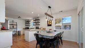 A modern kitchen with a central island, wooden flooring, and a dining area with chairs. - Boots & Barrels Ranch-2 master bedrooms,2 add'l bedrooms,3 baths, views, firepit (Paso Robles)