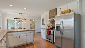 A modern kitchen with white cabinets, a stainless steel refrigerator, a wooden countertop, and a hanging light fixture. - Boots & Barrels Ranch-2 master bedrooms,2 add'l bedrooms,3 baths, views, firepit (Paso Robles)