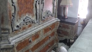 A bedroom with a large wooden dresser, a bedside table with a lamp, and a bed. - Cozy 1-bedroom house in beautiful Orlando with AC (Orlando)
