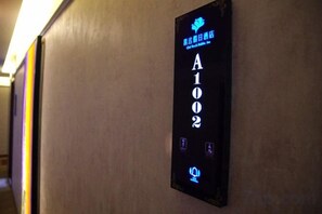 Hotellihuoneen numerokyltti, jossa on numero ’A102’ ja logo.