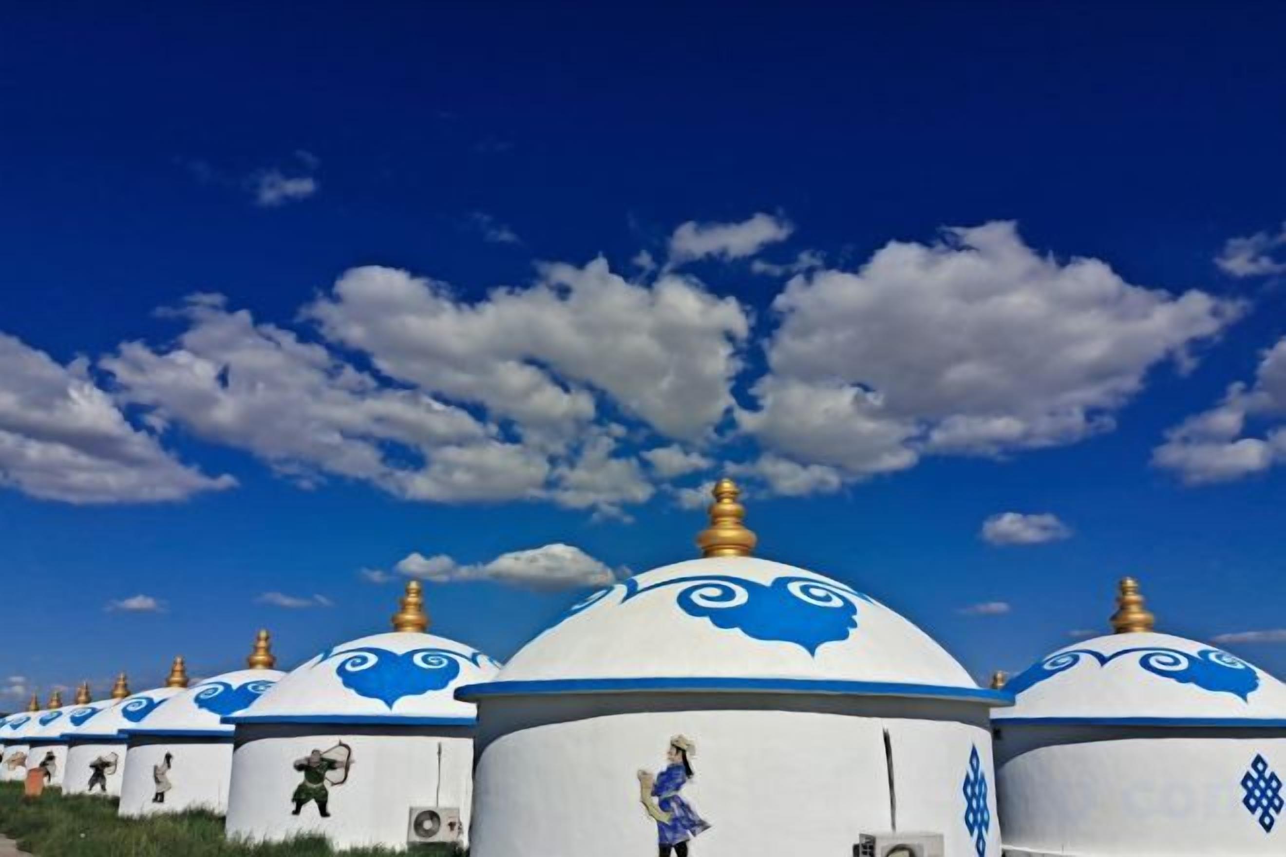 Una hilera de estupas blancas y azules con cúpulas doradas bajo un cielo azul despejado.