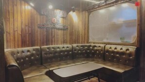 Una habitación con pared de madera, un ventanal grande y una zona de estar con una mesa.
