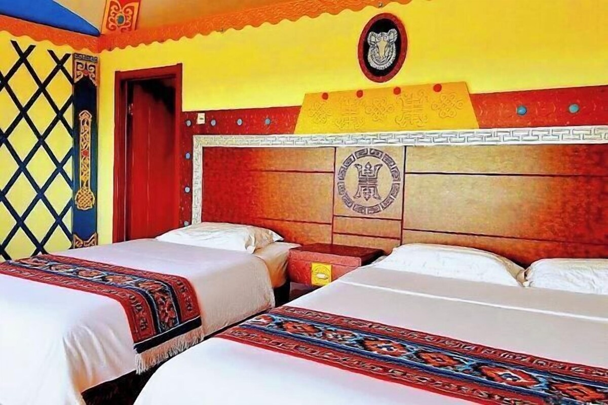 A hotel room with two beds, a wooden headboard, and a decorative wall panel.