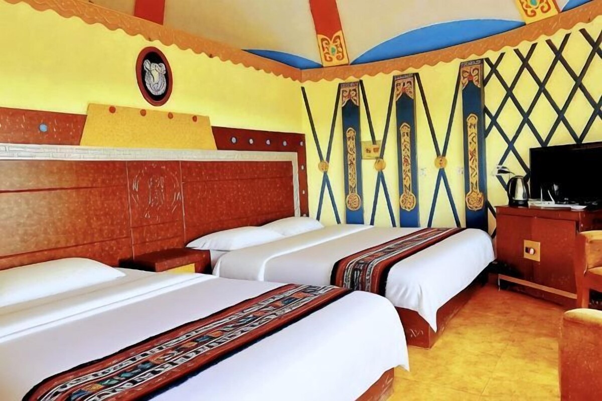 A hotel room with three beds, a television, and a desk with a chair.